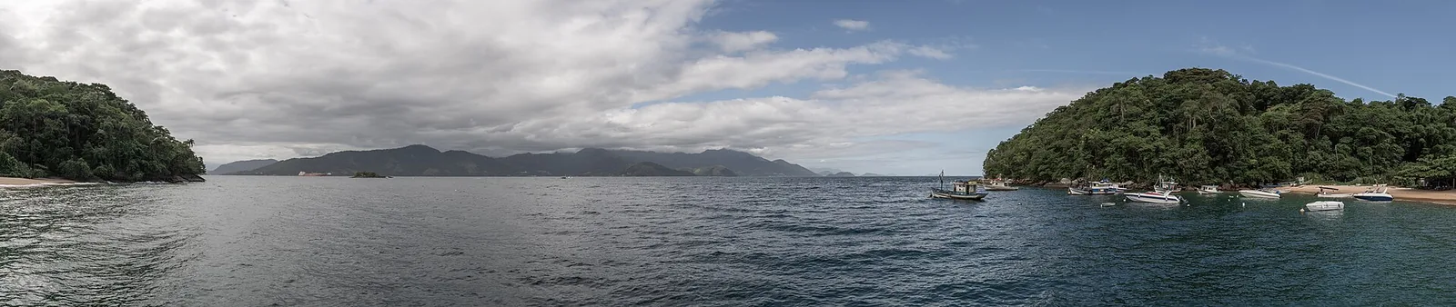 The forested island that guards Lopes Mendes — the beach sits on the exposed ocean side, a walk over the headland from the boat.